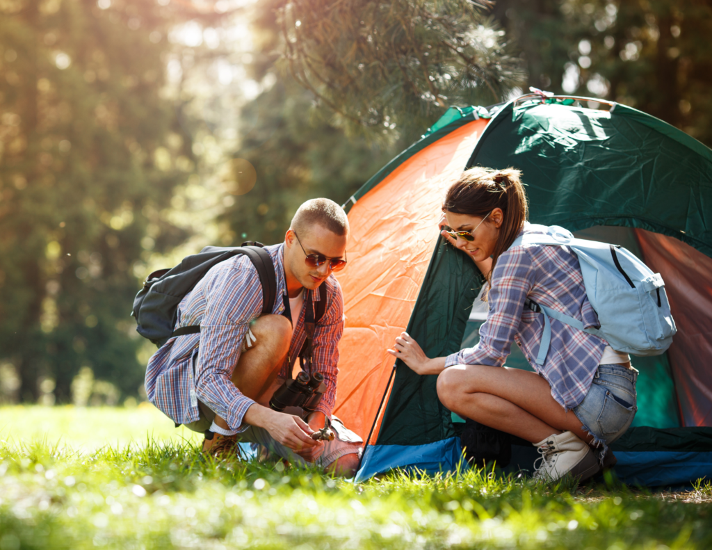 Couple Pitches A Tent In A Grassy Campground