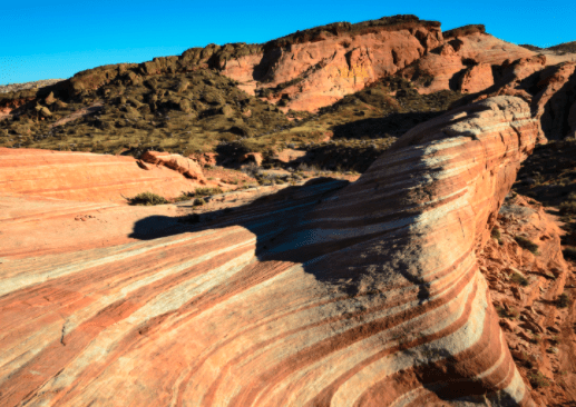Tan And Red Lines Swirl Throughout A Sandstone Cliff