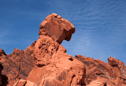 A Red Sandstone Rock Seems To Balance On Top Of A Tall Sandstone Column